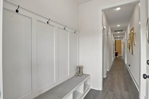 A hallway with white doors, a bench, and a coat rack.