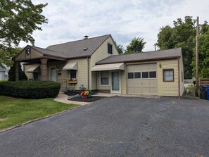 Ein zweigeschossiges Haus mit Garage, überdachter Veranda und Auffahrt.