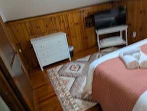 A bedroom with a bed, a dresser, and a television on a stand.