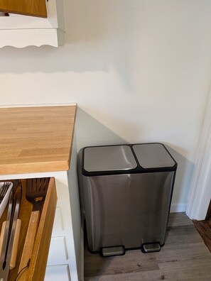 A kitchen corner with a wooden countertop, a stainless steel trash bin, and a white cabinet. - Comfy University View Cape Cod Includes a Hot Tub (Columbus)