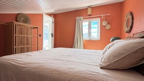A bedroom with a bed, a wardrobe, a window with curtains, and wall decorations. - House with a Sea View in Ericeira • Private Garden • 3 bedrooms (Ericeira)