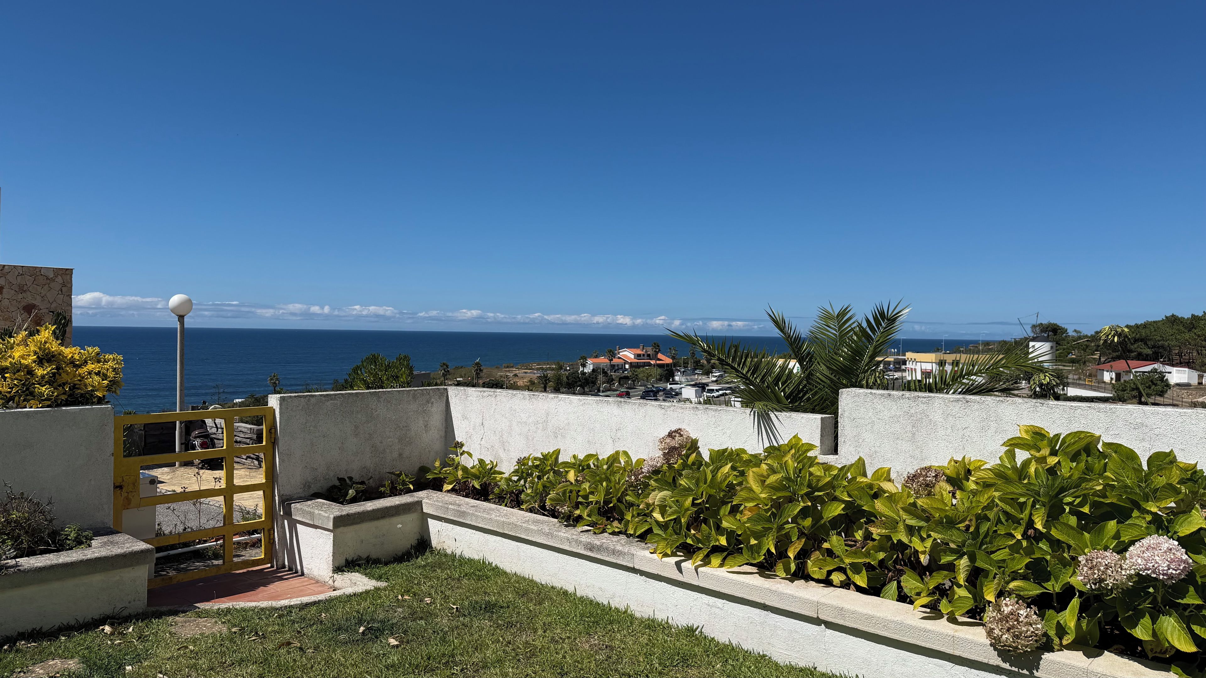 Una propiedad costera con vista al mar, un camino pavimentado y un jardín con plantas verdes.