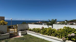 A coastal property with a view of the sea, a paved pathway, and a garden with green plants. - House with a Sea View in Ericeira • Private Garden • 3 bedrooms (Ericeira)