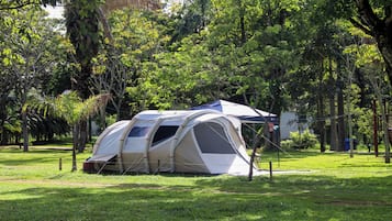 A camping tent set up in a grassy area with trees in the background.