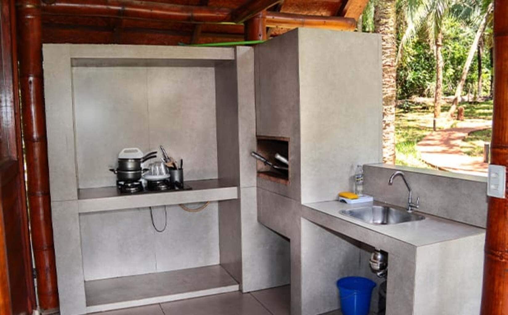 A compact kitchen with a gas stove, sink, and a blue trash bin.
