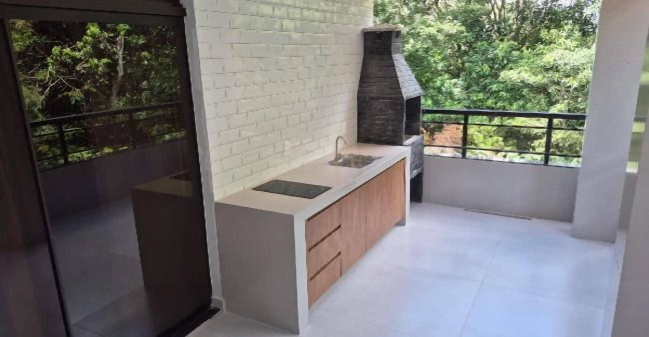 Un balcón con un lavamanos integrado, una chimenea de piedra y vistas a la vegetación.