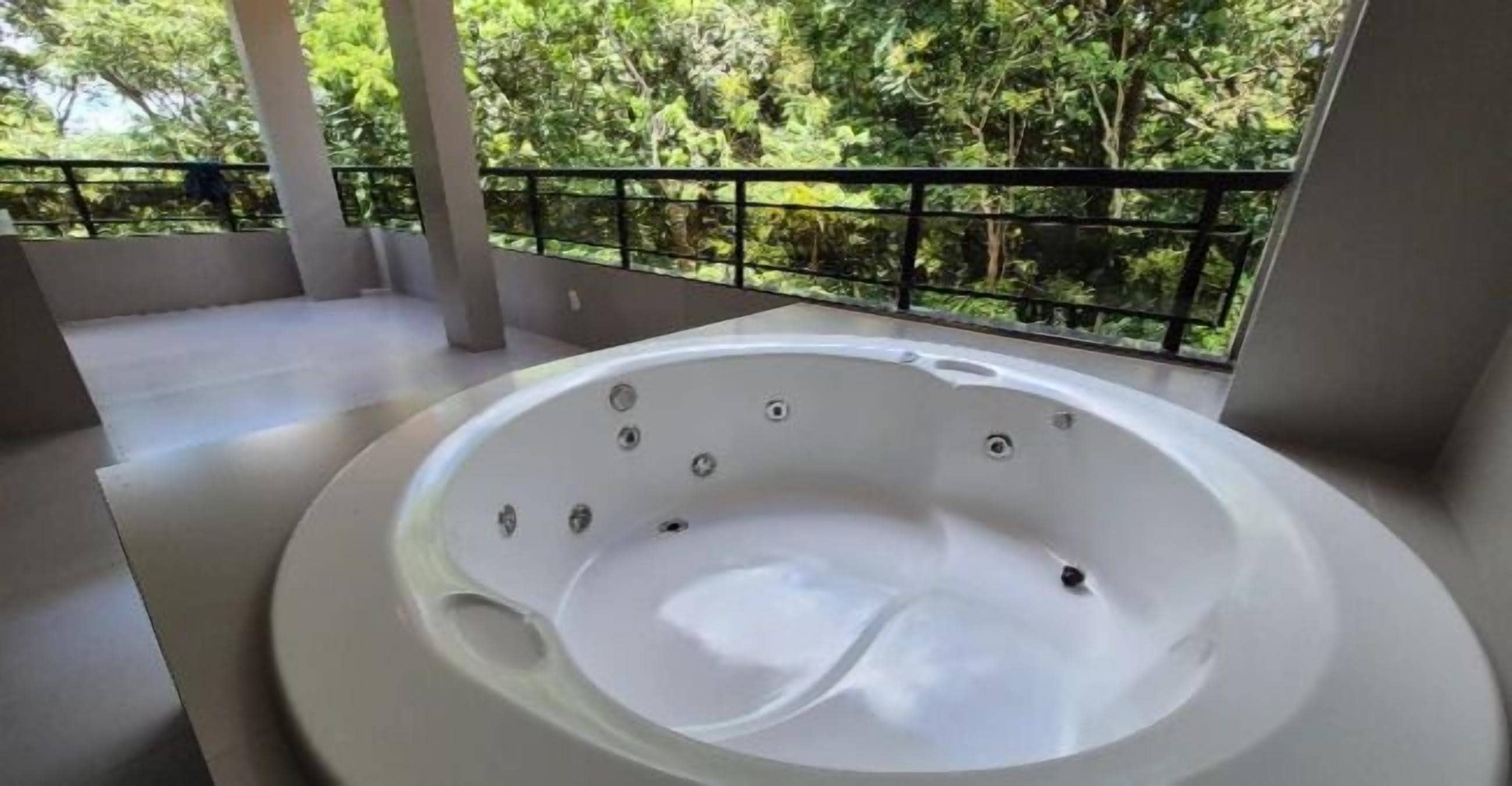 A hot tub on a balcony with a view of trees.