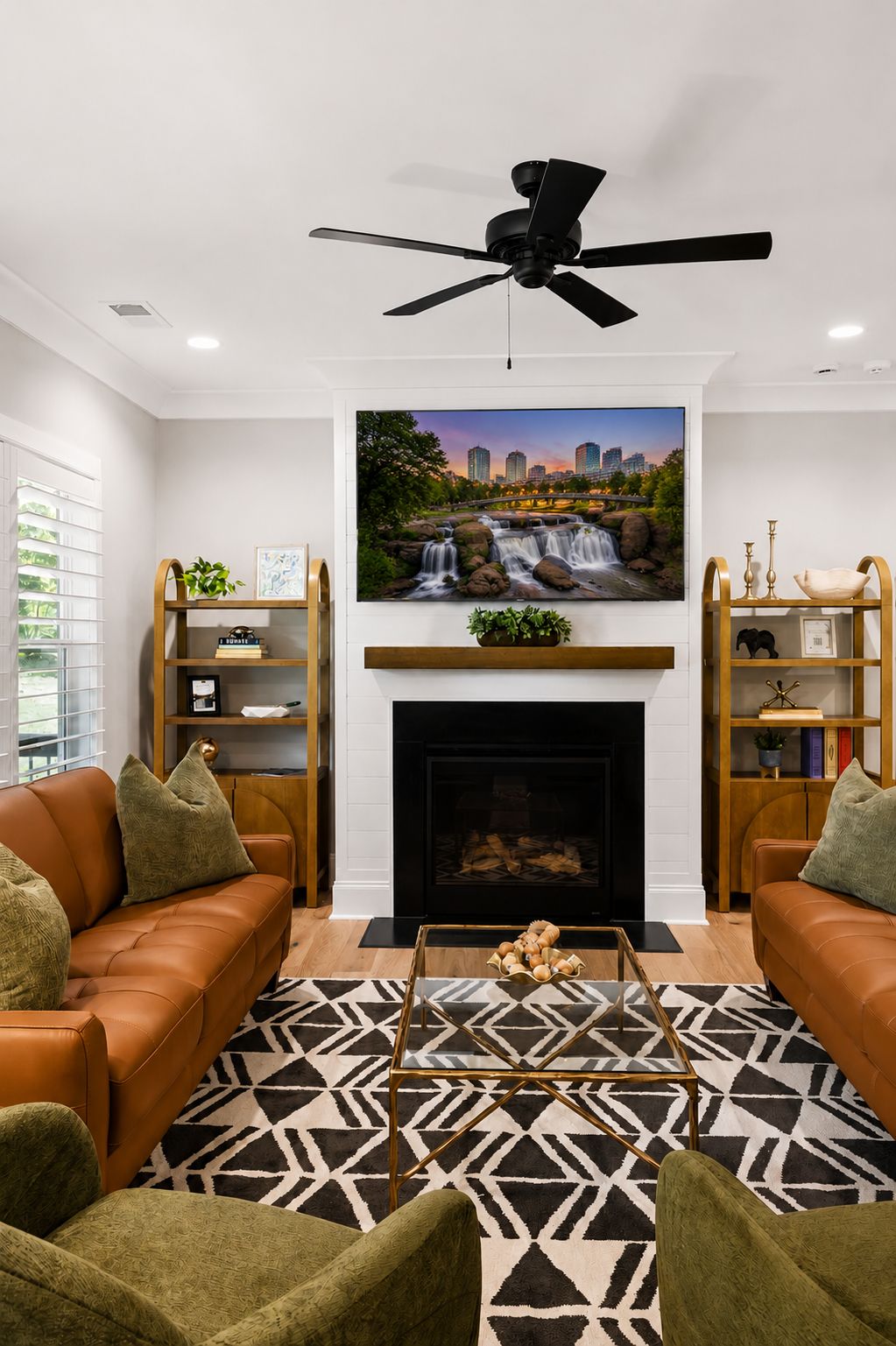 A living room with a fireplace, two sofas, a coffee table, and a television mounted above the fireplace.