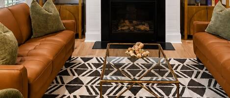 A living room with a fireplace, two sofas, a coffee table, and a television mounted above the fireplace.