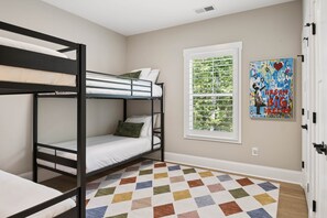 Ein Schlafzimmer mit Etagenbett, Fenster und farbenfroher Teppich.