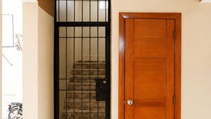 A hallway with a wooden door and a gate leading to a staircase. - Casa Nube | 8 min to SDQ Airport | Private Pool & Jacuzzi (Santo Domingo Este)