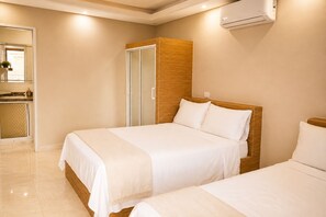 Ein Hotelzimmer mit zwei Betten, einem hölzernen Kopfteil, einem Badezimmer mit Spiegel und einer Klimaanlage.