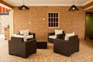 A room with two wicker sofas, a brick wall, a window, and hanging lights. - Casa Nube | 8 min to SDQ Airport | Private Pool & Jacuzzi (Santo Domingo Este)