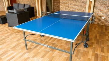 Un tavolo da ping pong su ruote, un divano e una parete in mattoni sullo sfondo.