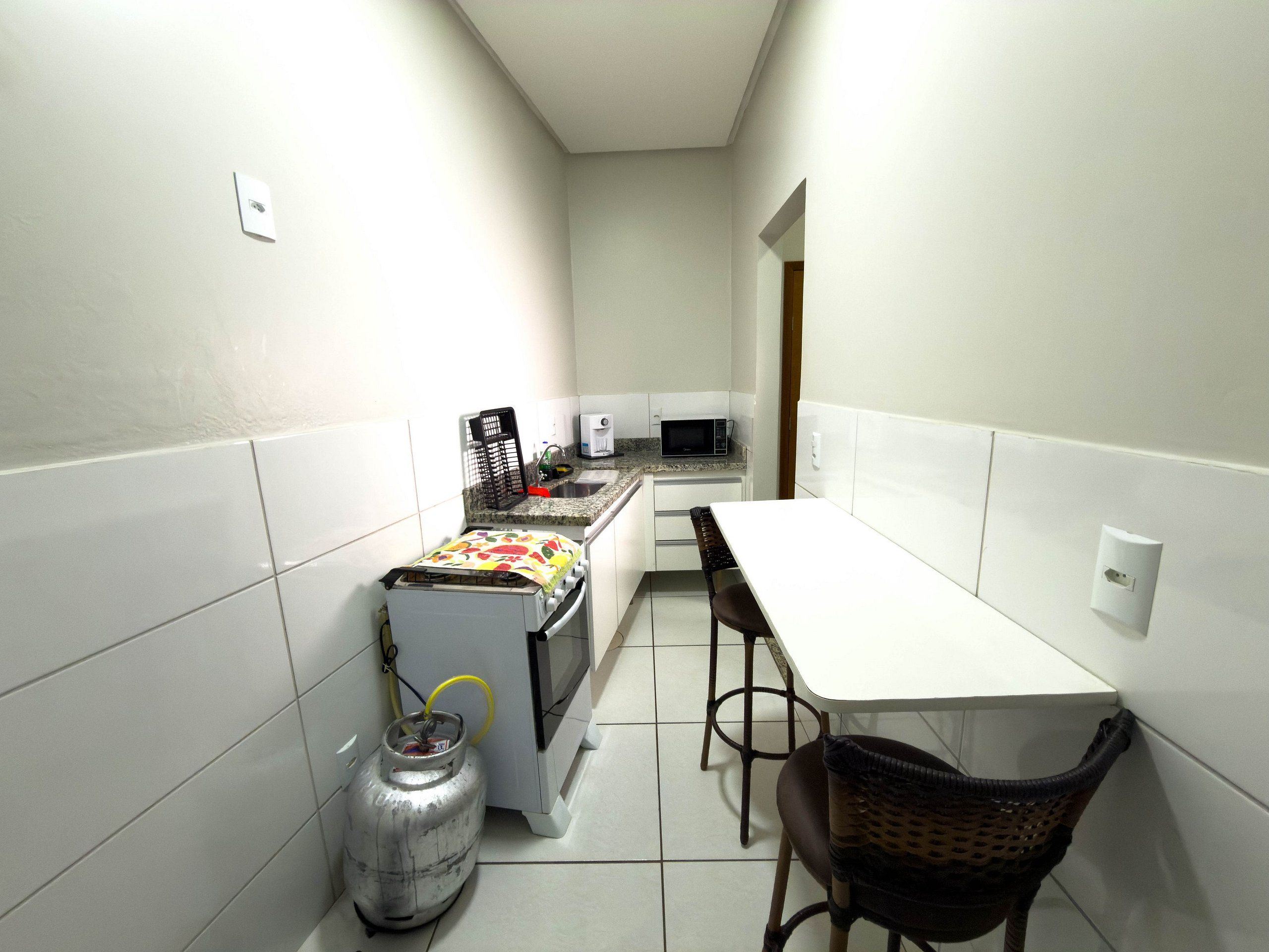 Una cocina compacta con estufa a gas, microondas y una pequeña mesa de comedor con sillas.