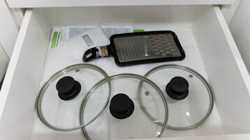 Un tiroir contenant un appareil électronique noir, qui pourrait être une râpe, ainsi que trois couvercles en verre transparent munis de boutons noirs.