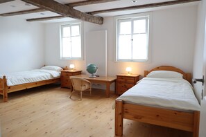 Un dormitorio con dos camas de madera, un escritorio con un globo terráqueo y una silla.