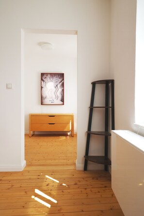 Ein Zimmer mit Holzboden, weißer Wand, einer Holzbank und einer an der Wand angelehnten Leiter.