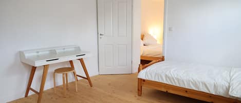 A bedroom with a wooden bed, a white desk, and a chair.
