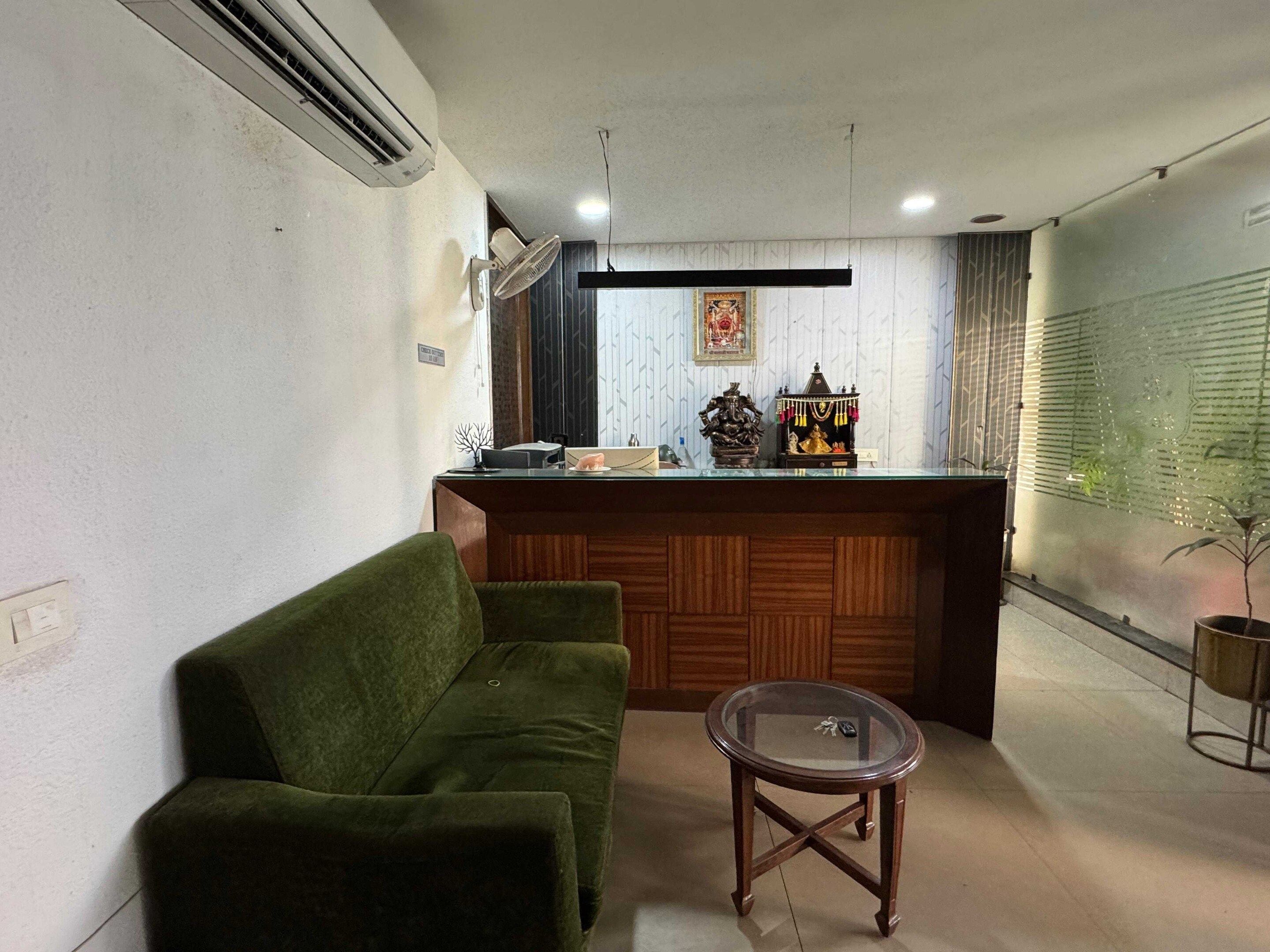 A reception area with a green sofa, a glass-top table, and a wooden reception desk.