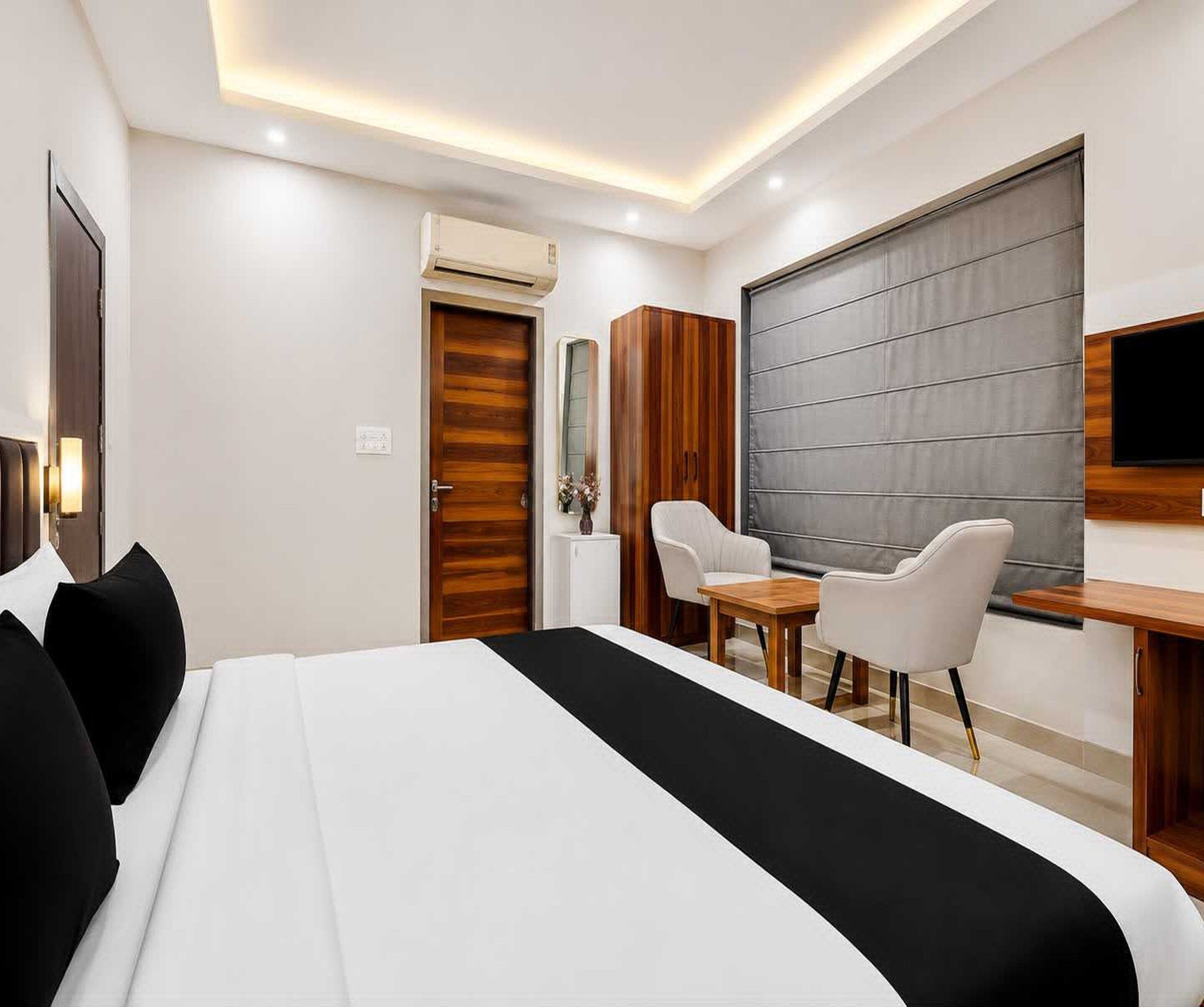 A modern hotel room with a large bed, a desk, a chair, and a television.