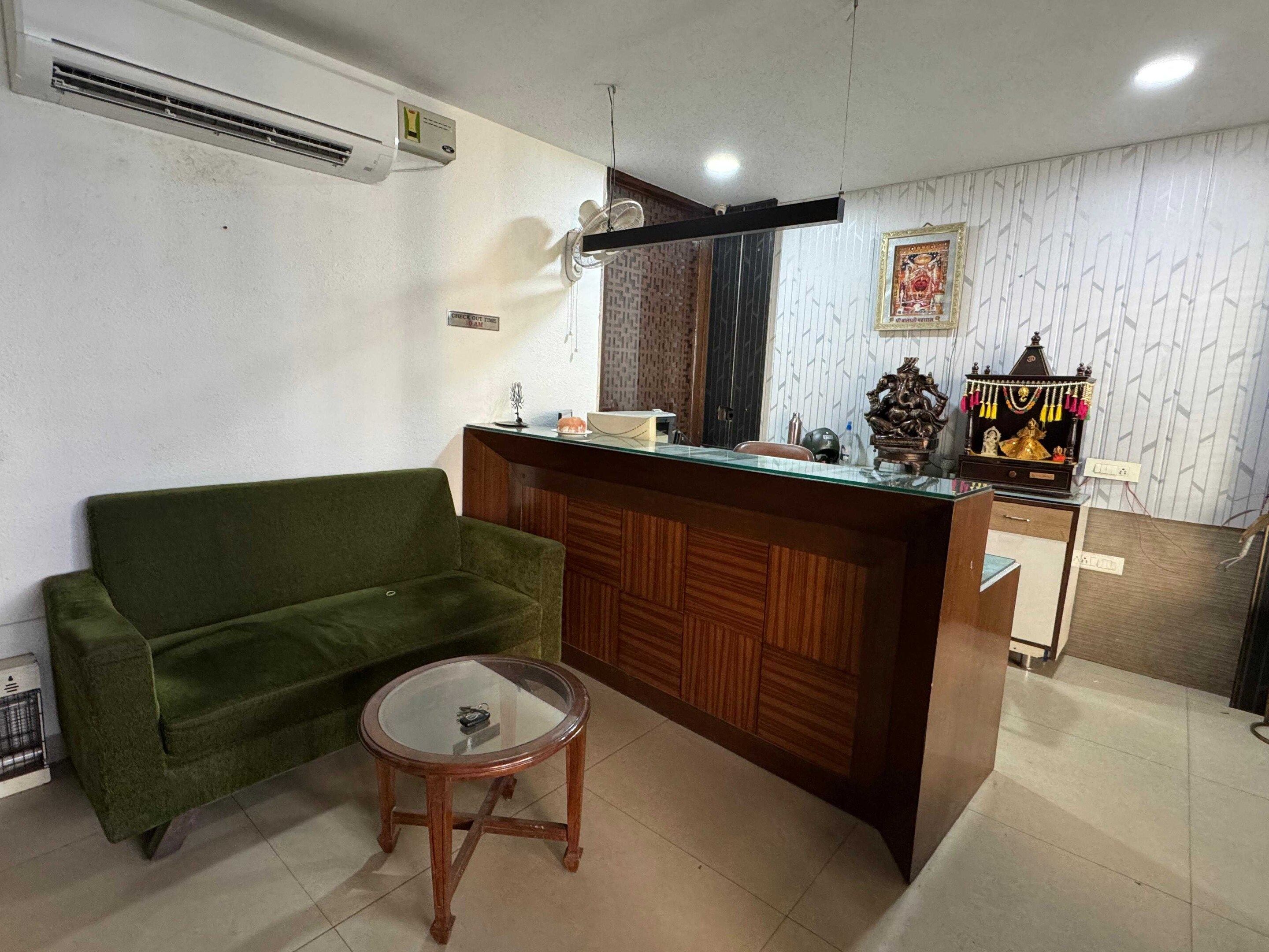 A room with a green sofa, a wooden reception desk, and a small glass table.
