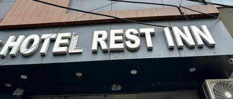 A hotel with a sign reading 'HOTEL REST INN' and multiple windows.