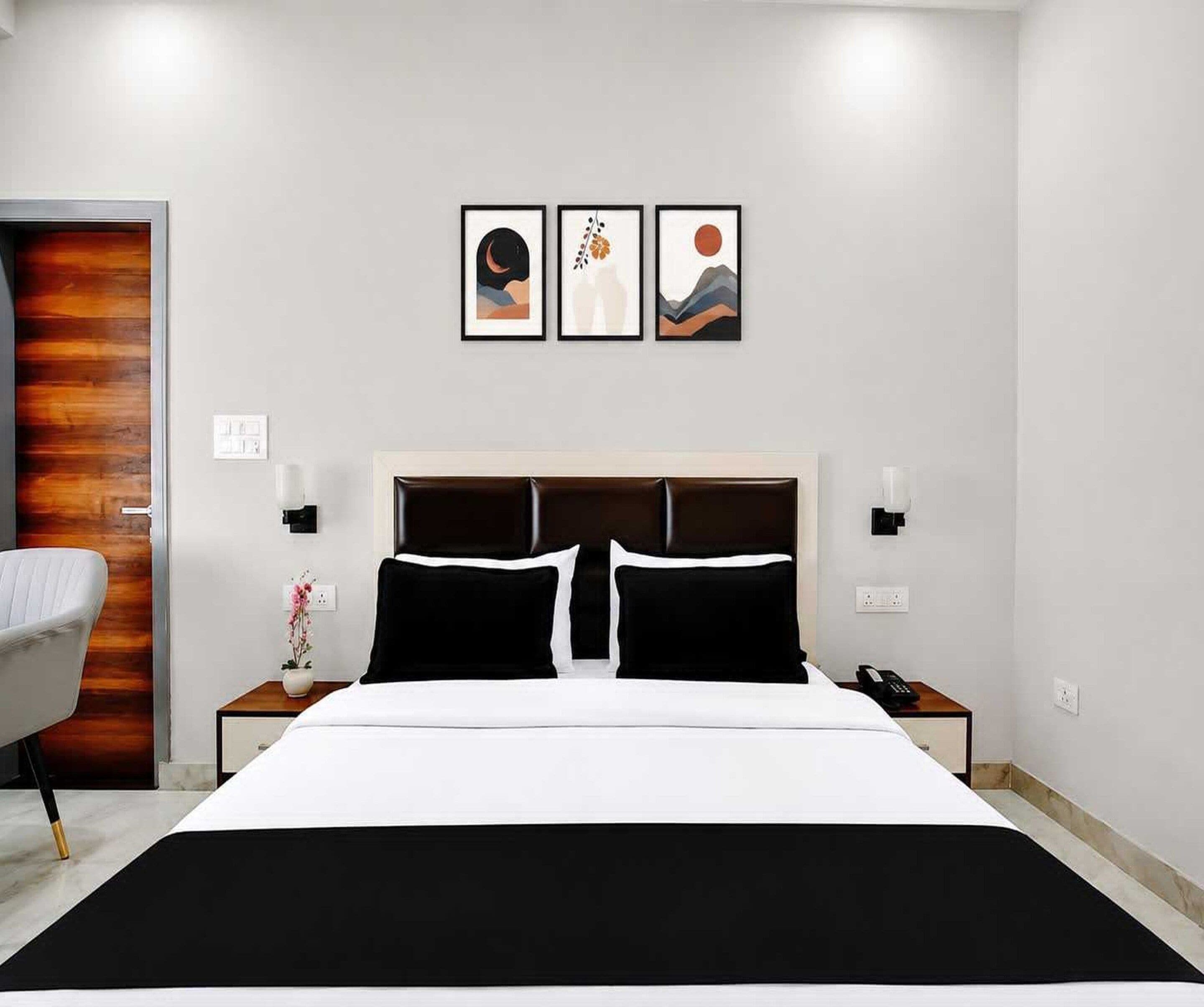 A hotel room with a bed, bedside tables, a chair, and artwork on the wall.