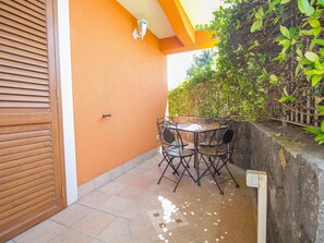 A patio with a table and chairs, a wooden door, and an orange wall. - 1-bed Suite With Private Patio (Trecastagni)