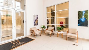 A hotel lobby with a reception desk, seating area, and large windows. - StayHome Rua Augusta - Heated Pool & Gym (São Paulo)