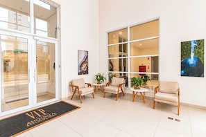 A hotel lobby with a reception desk, seating area, and large windows. - StayHome Rua Augusta - Heated Pool & Gym (São Paulo)