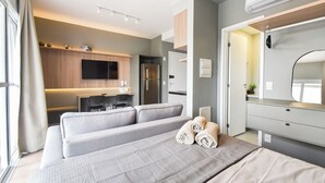 A modern hotel room with a bed, a desk, a flat-screen TV, and a built-in air conditioning unit. - StayHome Rua Augusta - Heated Pool & Gym (São Paulo)