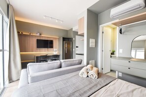 A modern hotel room with a bed, a desk, a flat-screen TV, and a built-in air conditioning unit. - StayHome Rua Augusta - Heated Pool & Gym (São Paulo)