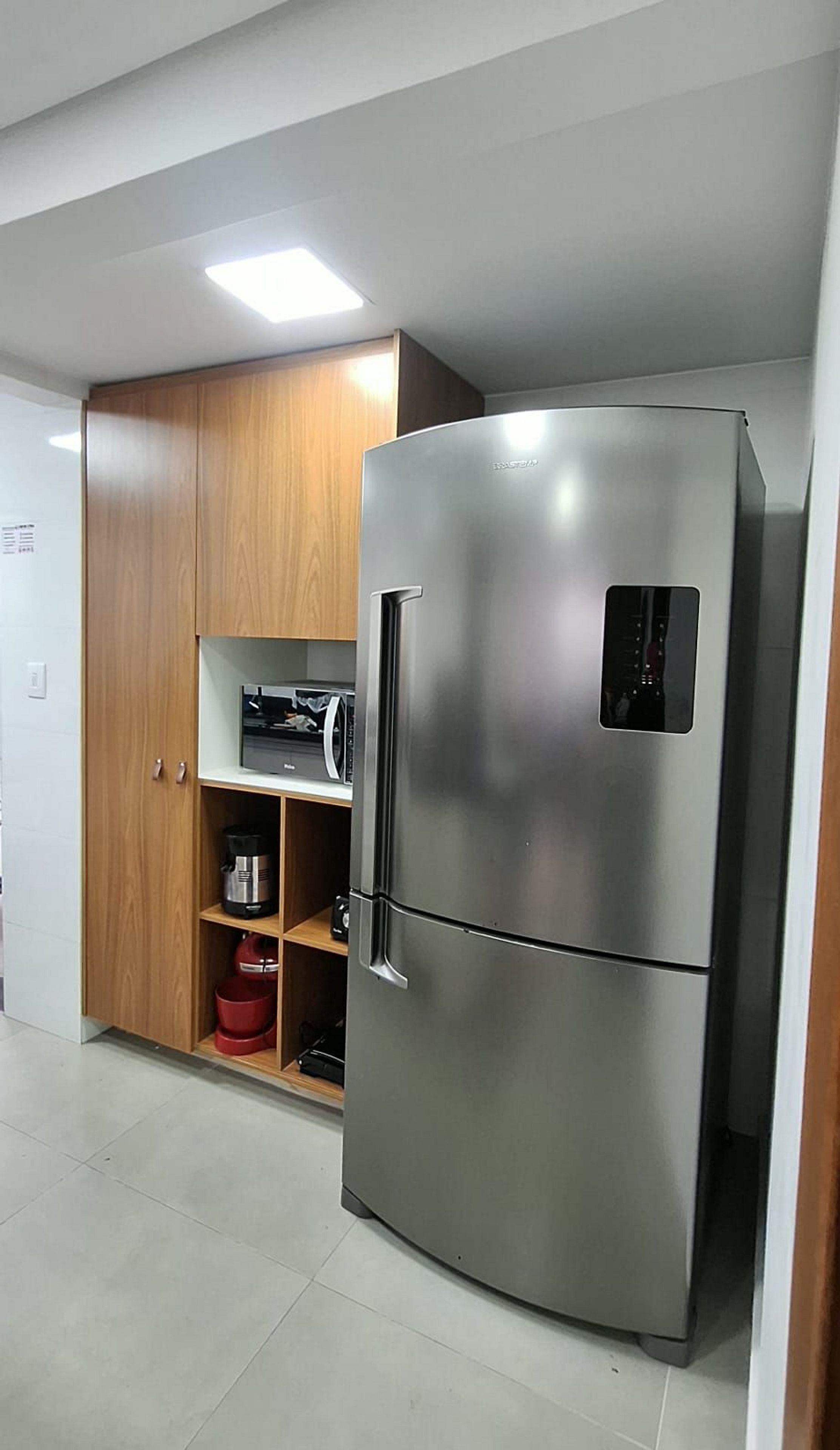 A kitchen with a stainless steel refrigerator, wooden cabinets, and a microwave.