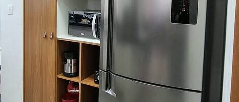 A kitchen with a stainless steel refrigerator, wooden cabinets, and a microwave.