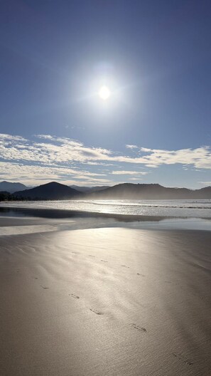 Uma praia com céu claro e sol brilhando.