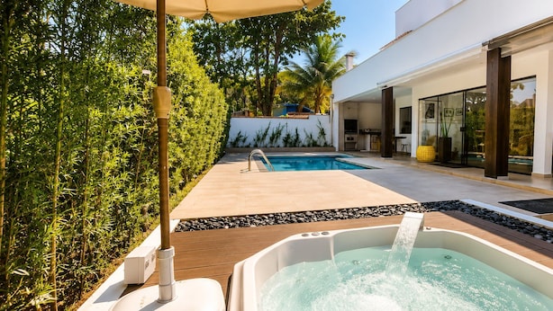 A modern outdoor pool area with a hot tub, wooden decking, and yellow chairs. - Villaggio 2 (São Sebastião)