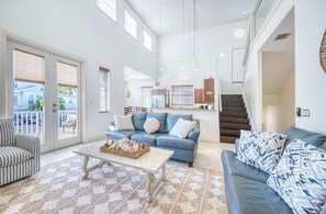 A spacious living room with a blue sofa, a striped armchair, and a coffee table. - Banana Cabana- Perfect Location (Holmes Beach)
