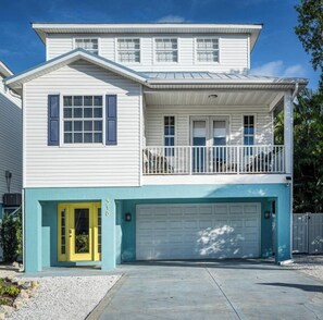 A two-story house with a garage, a balcony, and a yellow front door. - Banana Cabana- Perfect Location (Holmes Beach)