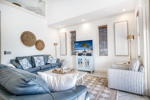 A modern living room with a grey leather sofa, a patterned armchair, a coffee table, and a television on a stand. - Banana Cabana- Perfect Location (Holmes Beach)