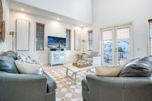 A living room with two leather sofas, a coffee table, and a TV on a cabinet. - Banana Cabana- Perfect Location (Holmes Beach)