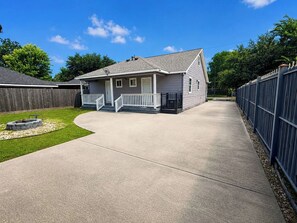 Ein Wohnhaus mit gepflasterter Auffahrt, umzäunter Garten und einer Veranda.