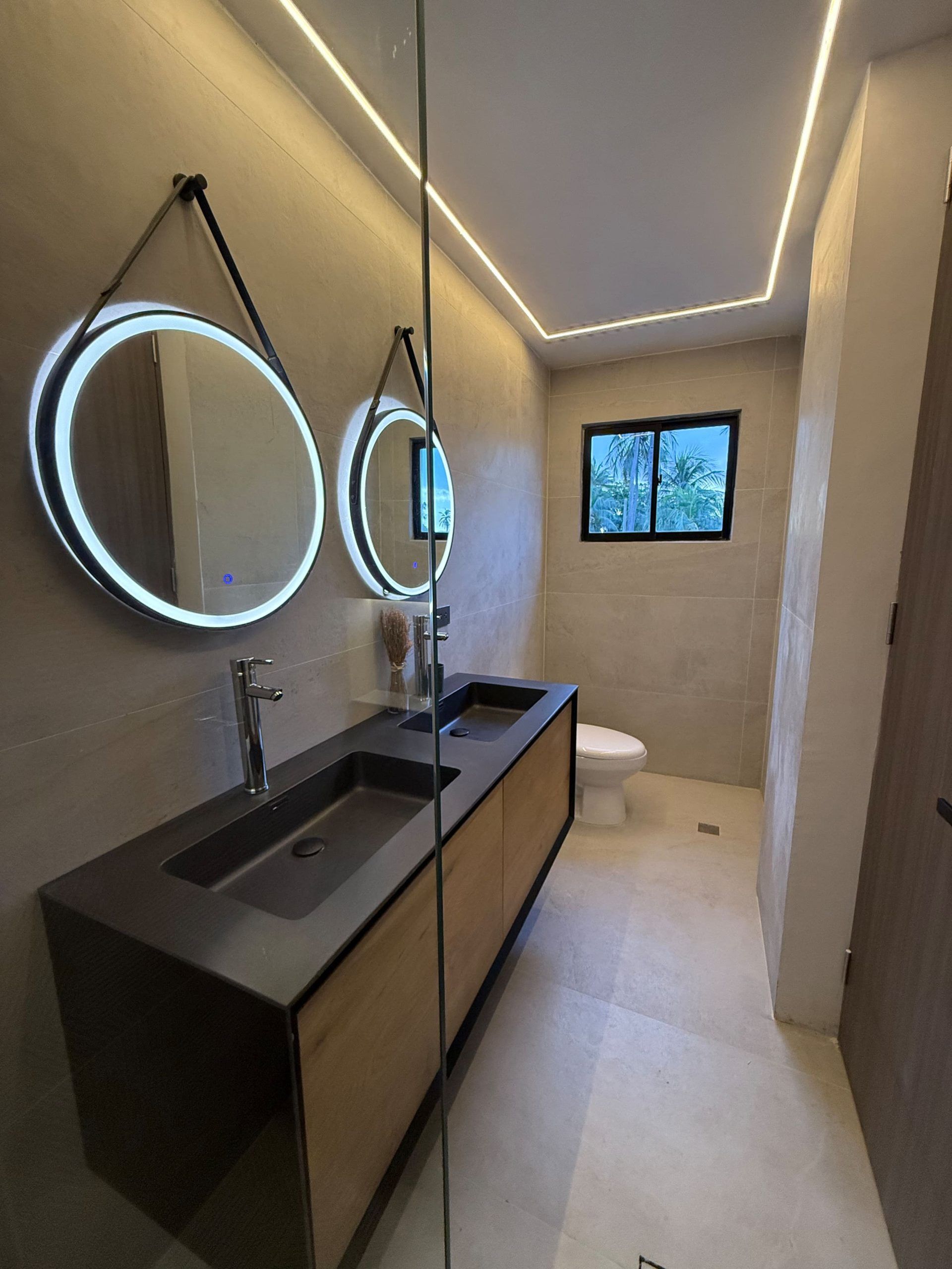 Un bagno moderno con uno specchio grande, due lavandini e un water.