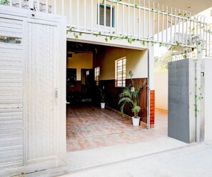 A gated entrance with a tiled patio, potted plants, and a wooden door. - Saver Double Hotel White Retreat Inn (Vikasnagar)