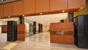 A modern hotel lobby with a polished marble floor, wooden reception desk, and glass doors leading to a hallway. - Townhouse Mindspace Road Gachibowli (Hyderabad)