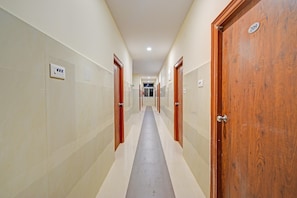 A corridor with doors on both sides, a tiled floor, and a ceiling with recessed lighting.