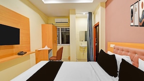 A hotel room with a bed, a desk with a phone, a chair, a bathroom with a sink, and a window. - Townhouse Mindspace Road Gachibowli (Hyderabad)