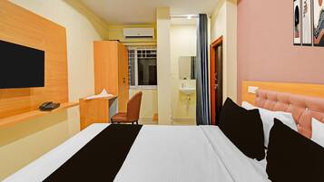 Una habitación de hotel con una cama, un escritorio con teléfono, una silla, un baño con lavamanos y una ventana.