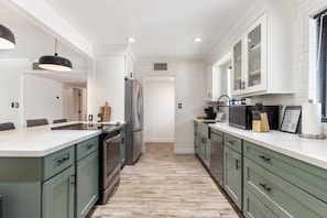 A modern kitchen with a central island, built-in appliances, and a herringbone wood floor. - Modern Scottsdale|Salt Pool + Hot Tub + Fire Pit (Scottsdale)