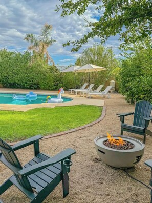 A backyard with a swimming pool, inflatable unicorn float, outdoor seating, and a fire pit. - Modern Scottsdale|Salt Pool + Hot Tub + Fire Pit (Scottsdale)